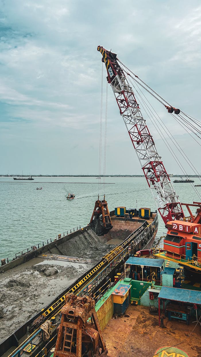 portfolio-03 A large crane operating on a vessel during an industrial dredging operation in a harbor.